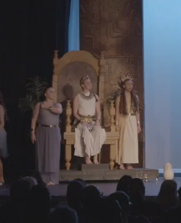 Three performers onstage in front of the finished golden throne.